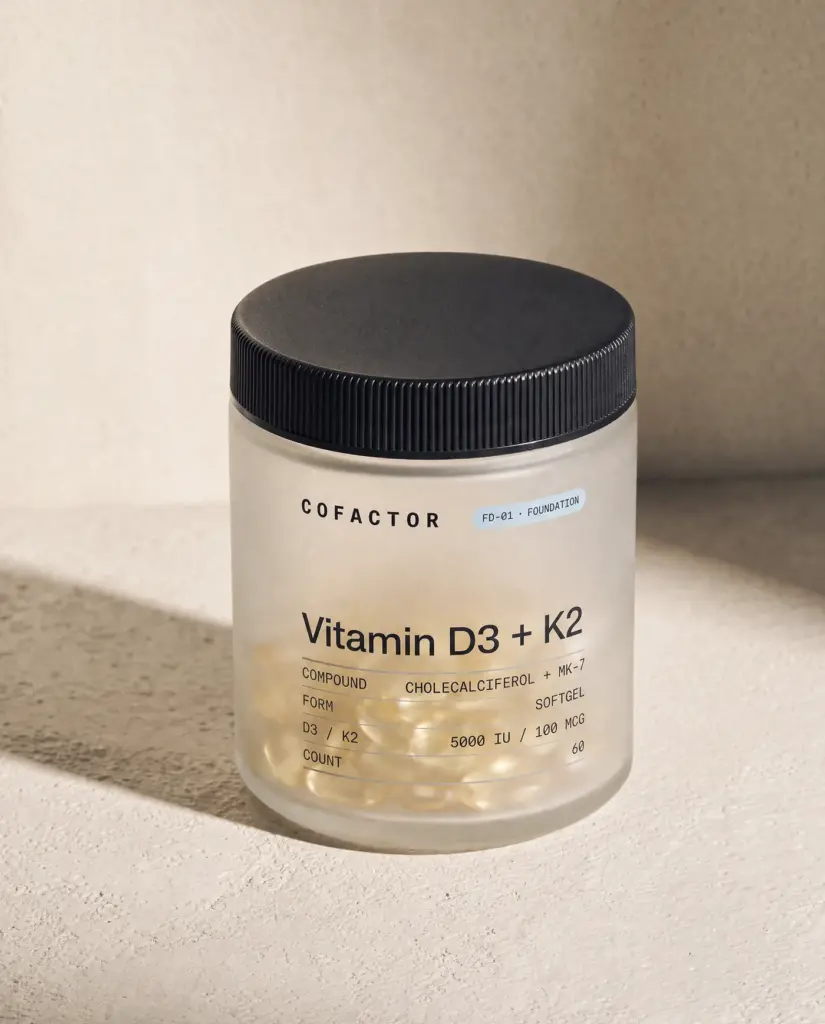 Vitamin D3 + K2 jar at a three-quarter angle, frosted glass with a matte black cap.