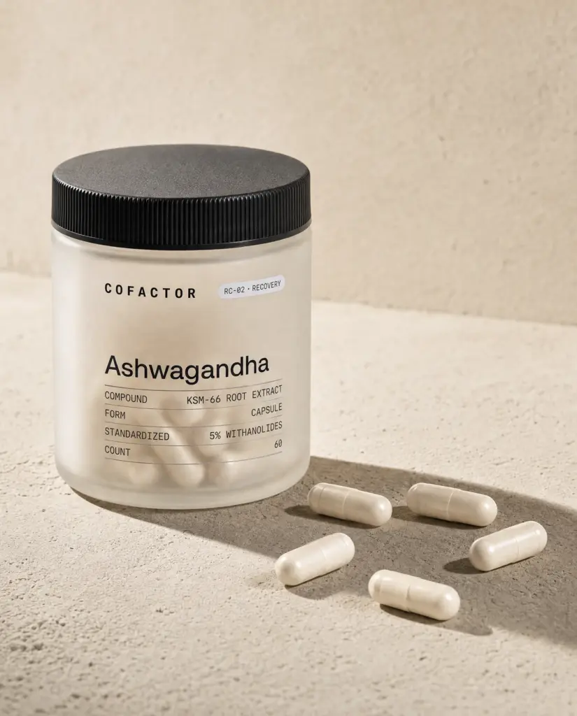 Ashwagandha jar with several capsules on the surface beside it.